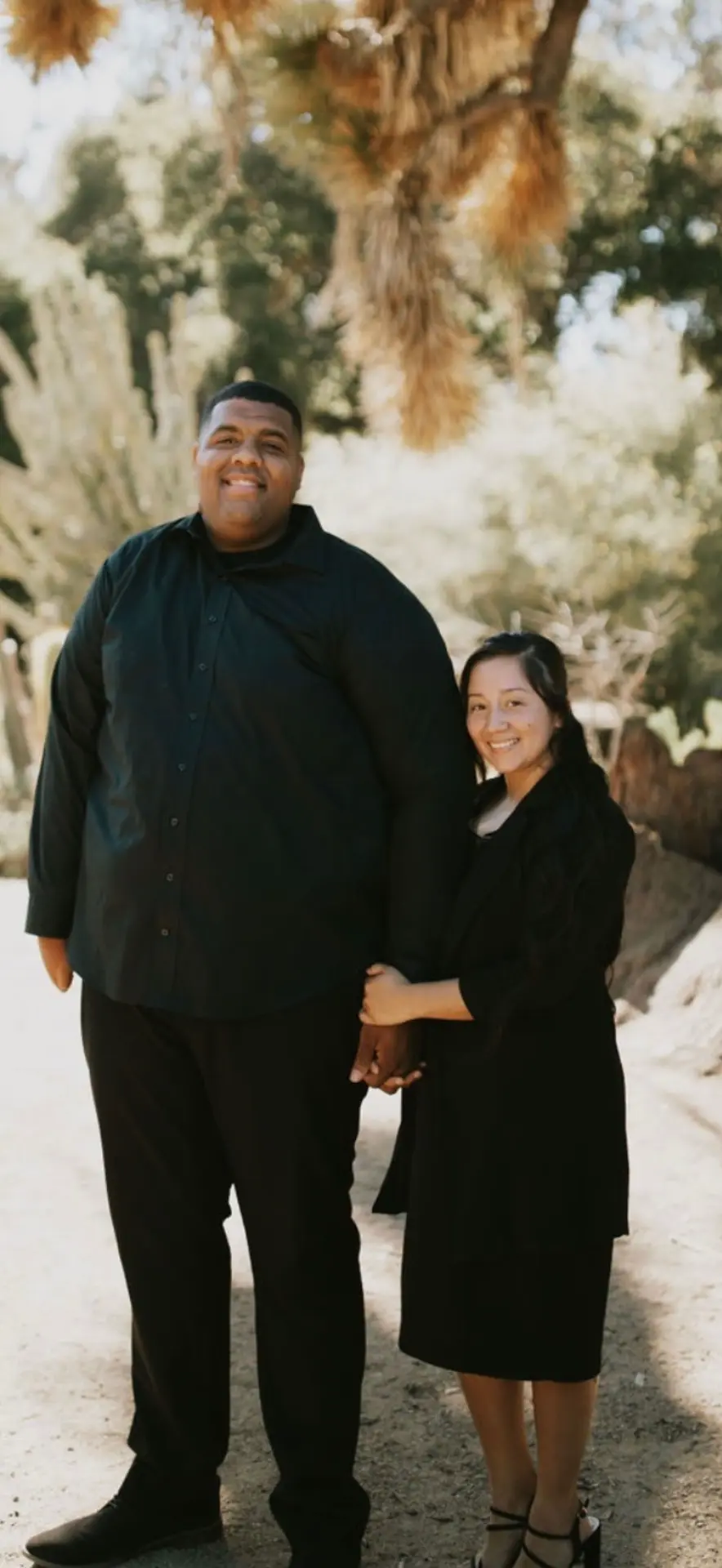 Camp speaker Evan Moore with his wife, standing outdoors beneath a tree